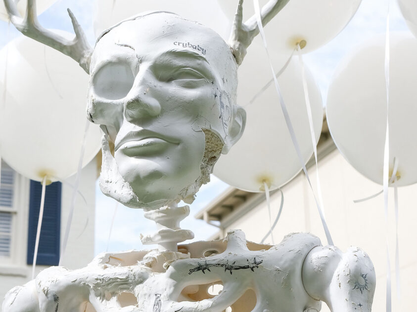 Dearman by Bradly Brown: plaster-coated skeleton with antlers and white balloons