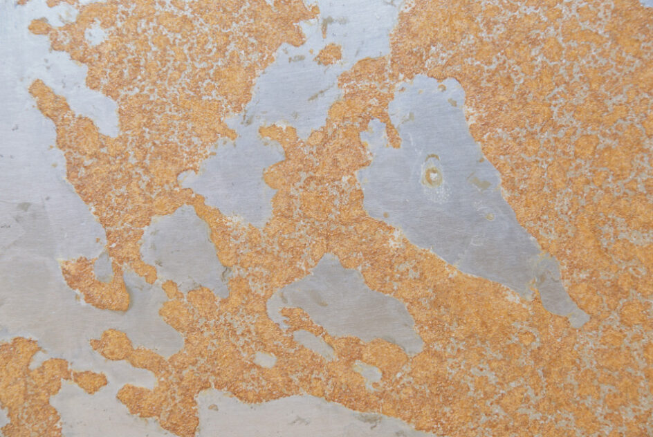 Close-up of orange rust patterns on bare steel. As Impala Murder by Bradly Brown